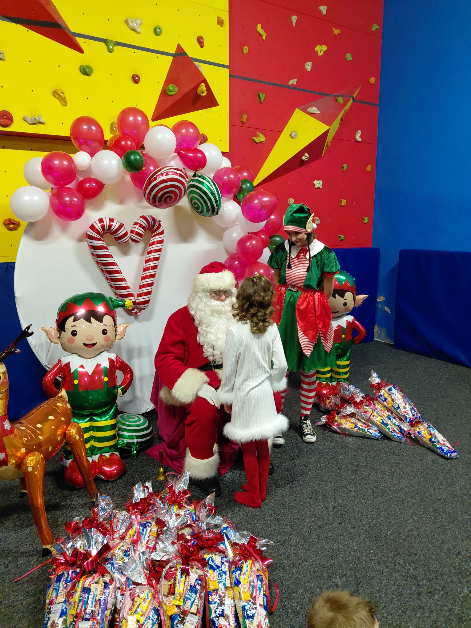 Mała dziewczynka stoi przed Świętym Mikołajem w świątecznej scenerii.